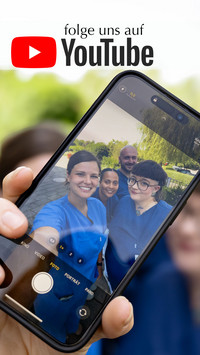 Vier Pfleger:innen halten ein Mobiles Telefon in die Kamera